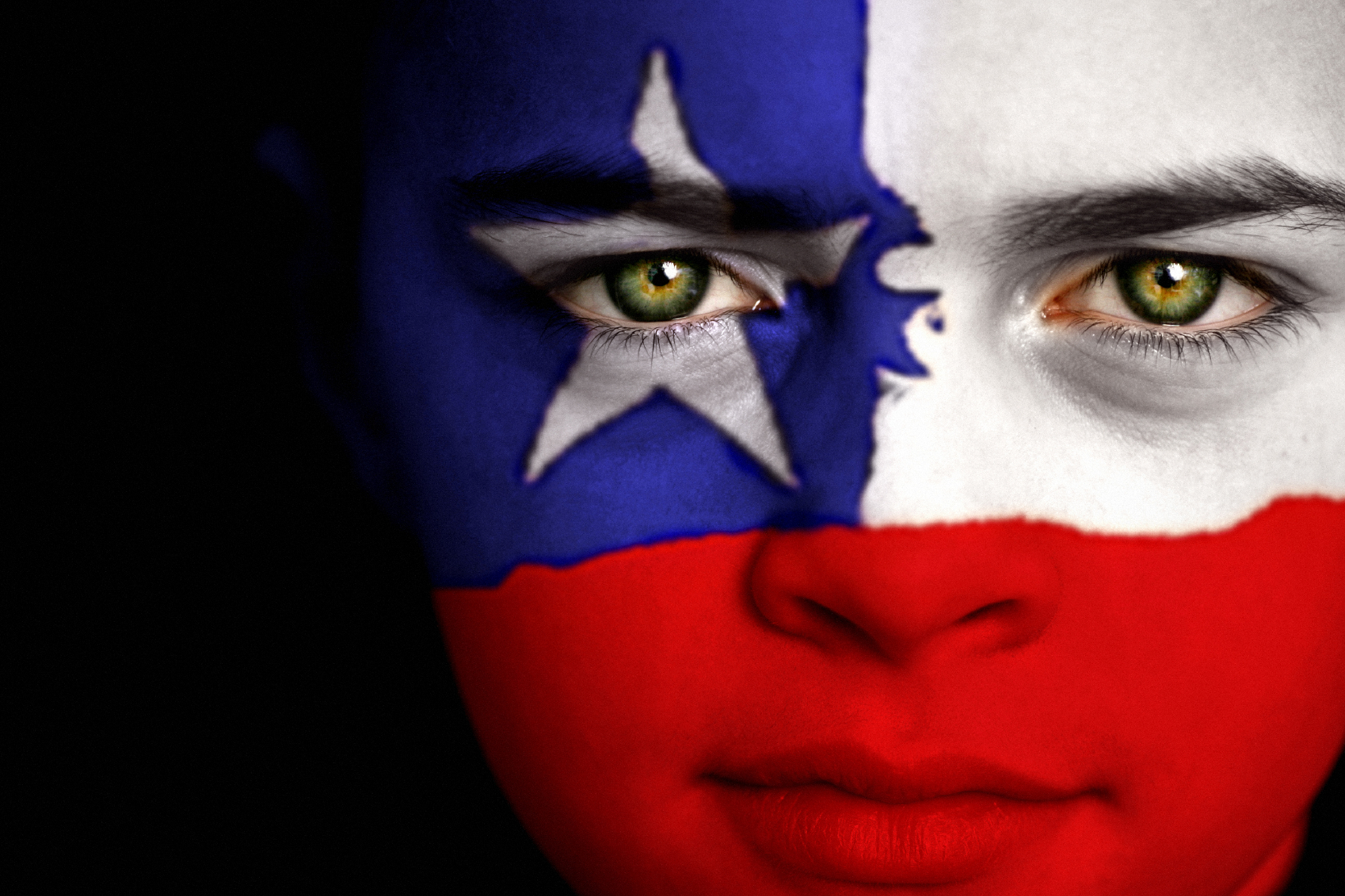Portrait of a boy with the flag of Chile painted on his face.