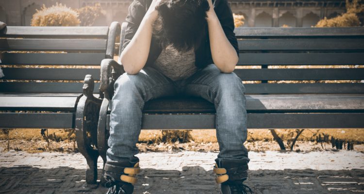 migraines-man-in-black-shirt-and-gray-denim-pants-sitting-on-gray